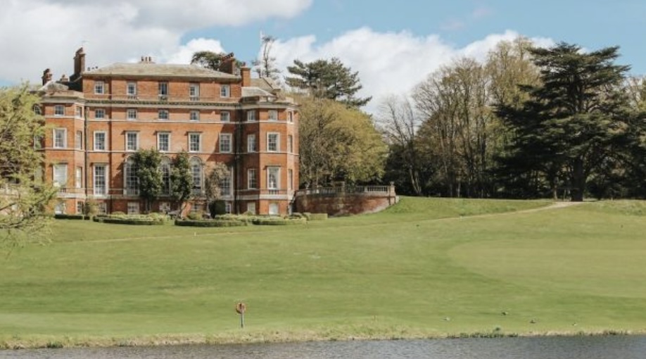 Brocket Hall Golf Club, Hertfordshire, UK - Golf course green and large period clubhouse with trees