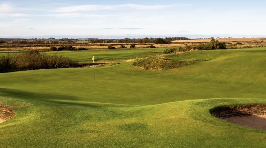 Goswick Links Golf Club, Northumberland - View of open field golf course with central putting green with bunker and fairway leading to open countryside in the distance