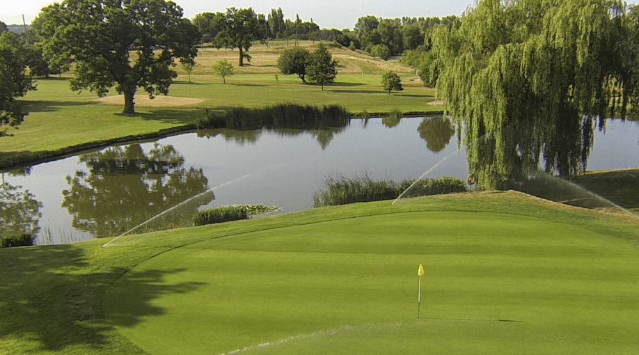 Horton Park Golf Club, Surrey, - elevated view of golf course from behind green looking back across lake and fairway with sporadic trees